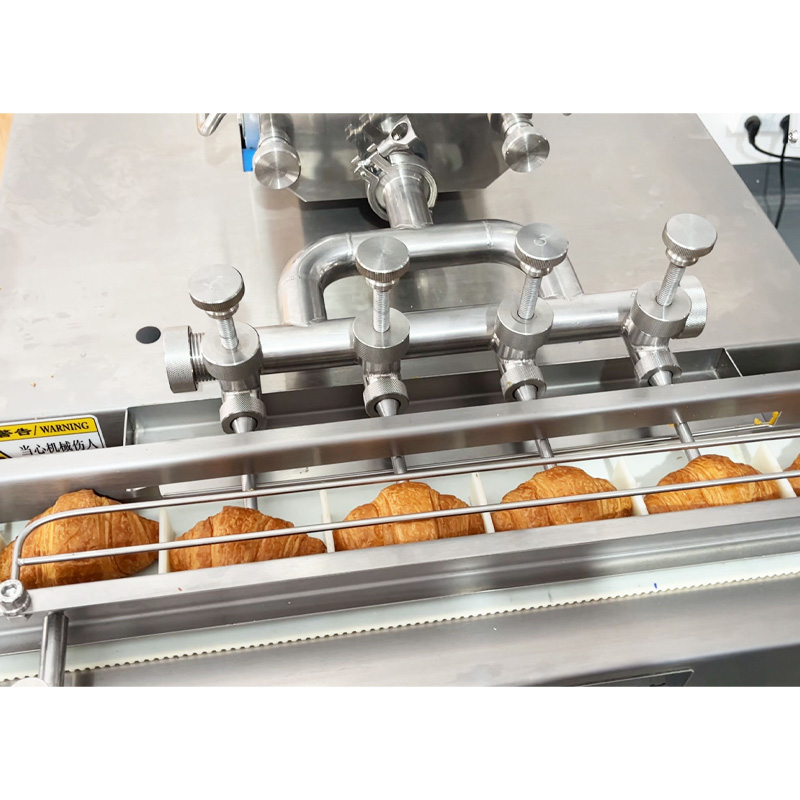 Close-up of bakery products being filled by the cream filling machine
